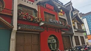 A traditional building with a red facade, a signboard, and a balcony with flowers. - Hanting Hotel (Linchuan No. 2 Middle School) (Fuzhou)