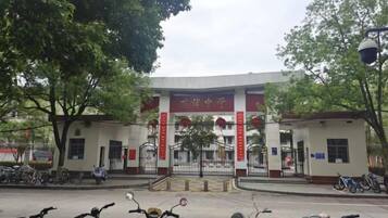 A building entrance with a red and white sign, a gated driveway, and several parked scooters.