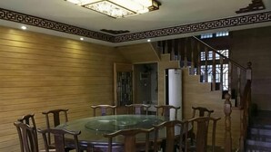 A dining area with a glass-top table and wooden chairs, a staircase, and a patterned ceiling. - Dongping Resort (Shanghai)