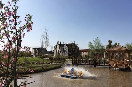 A water fountain with a gazebo in a park setting.. Dongping Resort