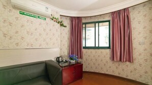 A room with a green sofa, a red cabinet, a window with pink curtains, and floral wallpaper. - Chunxin Hostel (Shanghai)