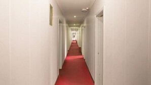 A long, narrow hallway with white walls and a red carpet. - Chunxin Hostel (Shanghai)