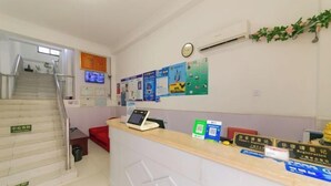 A reception area with a desk, a computer, and informational posters on the wall. - Chunxin Hostel (Shanghai)