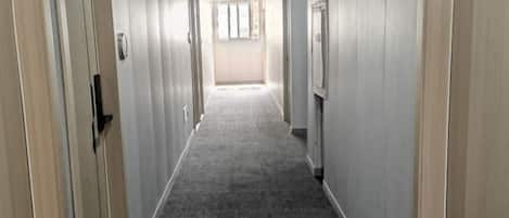 A long, narrow hallway with carpeted floors and doors on both sides.