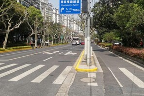 A street view with a pedestrian crossing, a directional sign, and a yellow curb. - Huashuyi Hostel (Shanghai Kongjiang Road) (Shanghai)