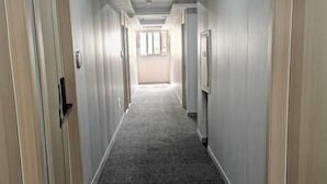 A long, narrow hallway with light-colored walls and a dark carpet. - Huashuyi Hostel (Shanghai Kongjiang Road) (Shanghai)