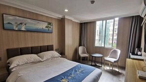 A hotel room with a large bed, a desk, two chairs, a painting on the wall, and a window with curtains. - Huashuyi Hostel (Shanghai Kongjiang Road) (Shanghai)