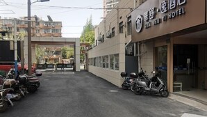 A hotel entrance with a sign in Chinese characters, a gated driveway, and parked scooters. - Huashuyi Hostel (Shanghai Kongjiang Road) (Shanghai)
