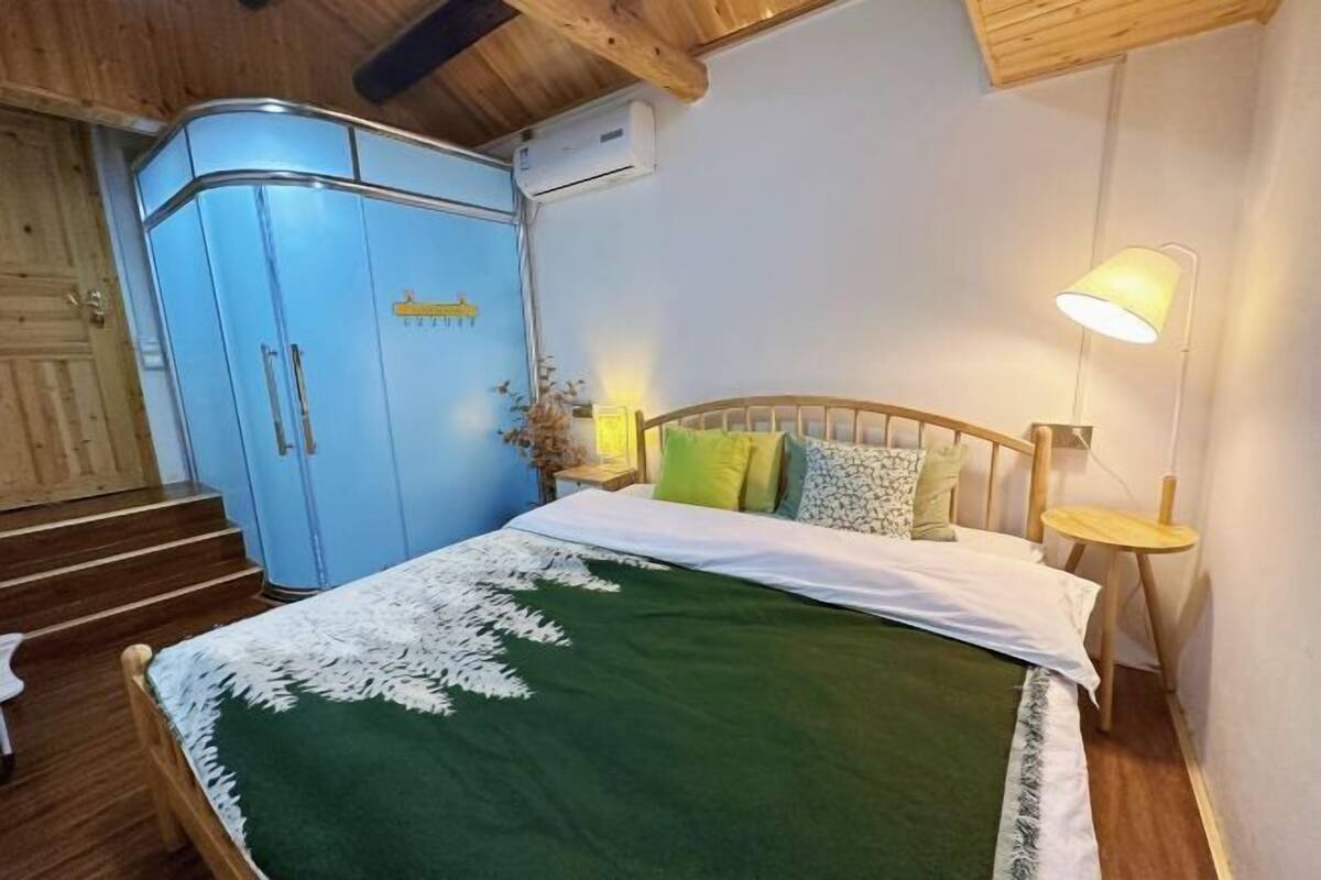 Una camera da letto con un letto, un armadio, un comodino, una lampada e una scala.
