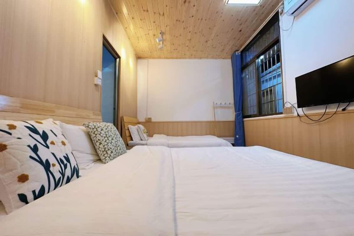 Camera d'albergo con pareti in legno, un letto con biancheria bianca, una TV a schermo piatto montata a parete e una finestra con tende blu.