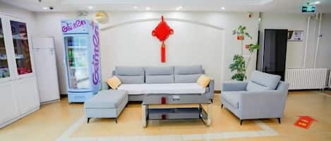A hotel lobby with a sofa set, a vending machine, and a red decorative item on the wall.