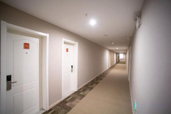 A long, narrow hallway with white doors, each marked with a number.