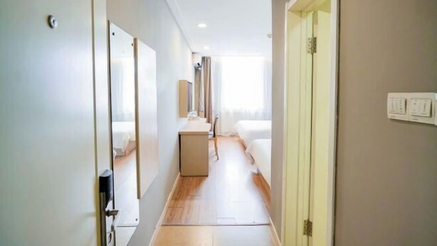A hotel corridor with a bed, a desk, and a mirror. - Homeinn Pebble Hotel (Qingdao North Station Licun Pedestrian Street) (Qingdao)