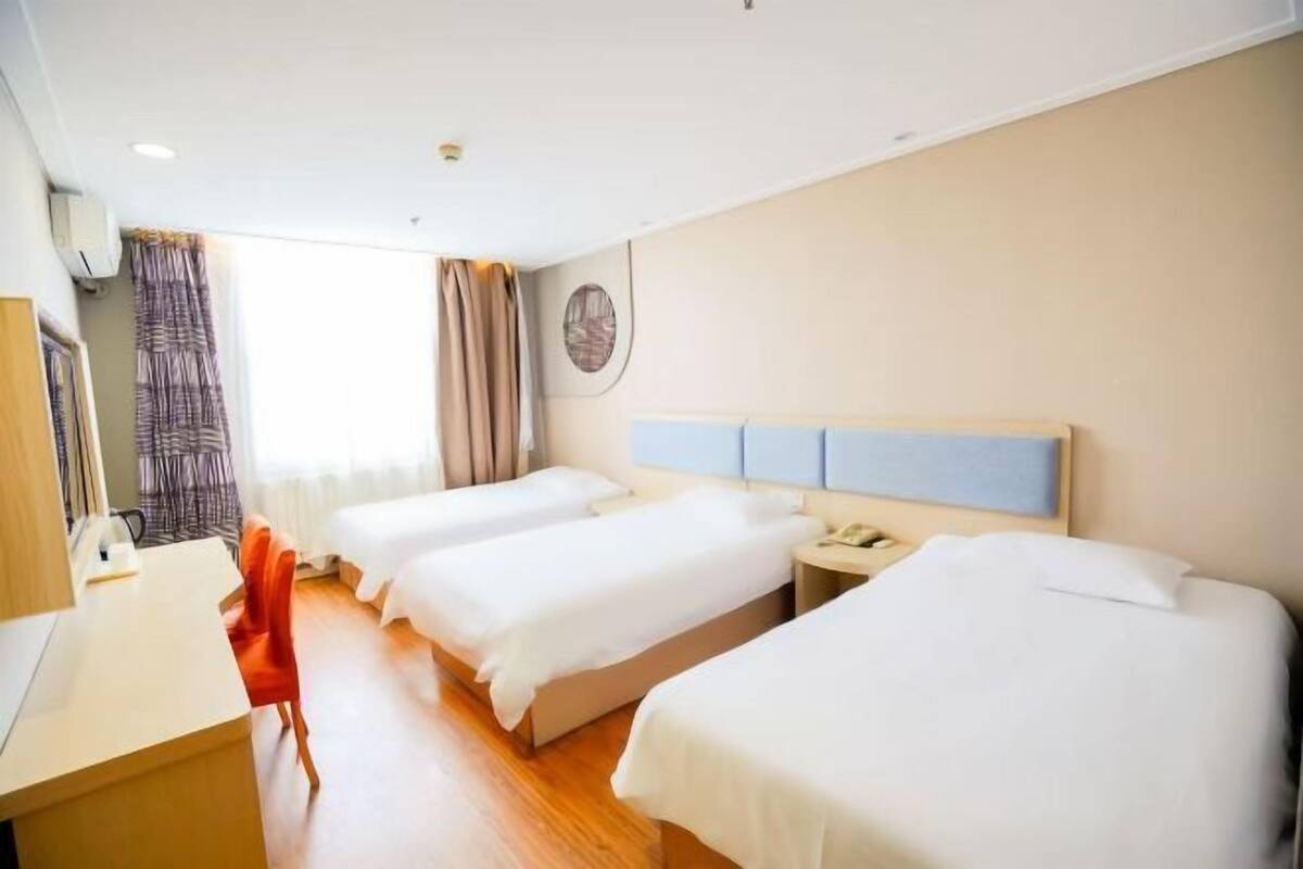 A hotel room with three beds, a desk, and a chair.