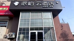 A hotel facade with a large glass entrance, a black sign with white text, and air conditioning units on the left. - Homeinn Pebble Hotel (Qingdao North Station Licun Pedestrian Street) (Qingdao)