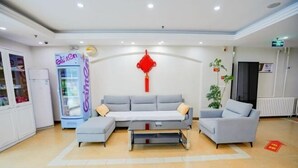 A reception area with a grey sofa, a small table, and a vending machine. - Homeinn Pebble Hotel (Qingdao North Station Licun Pedestrian Street) (Qingdao)