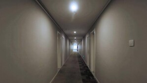 A long, narrow hallway with a carpeted floor and white walls. - Homeinn Pebble Hotel (Qingdao North Station Licun Pedestrian Street) (Qingdao)
