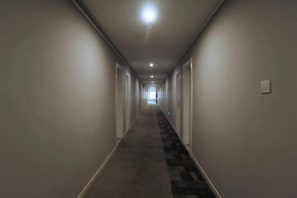 A long, narrow hallway with a carpeted floor and white walls. - Homeinn Pebble Hotel (Qingdao North Station Licun Pedestrian Street) (Qingdao)