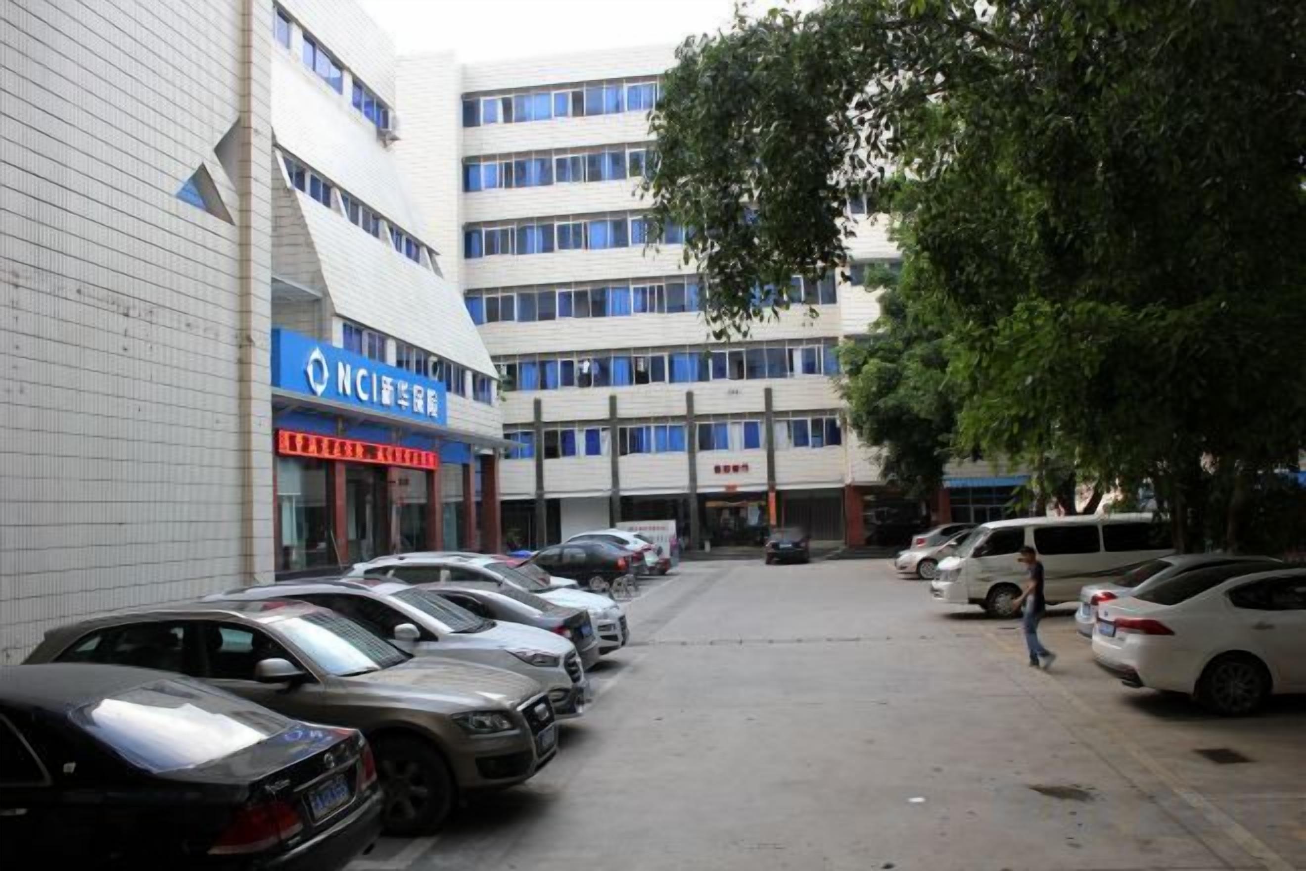 A parking lot with multiple cars, a building with signage, and a pedestrian walking by.