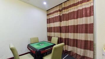 A room with a table and chairs, a patterned curtain, and a ceiling vent.