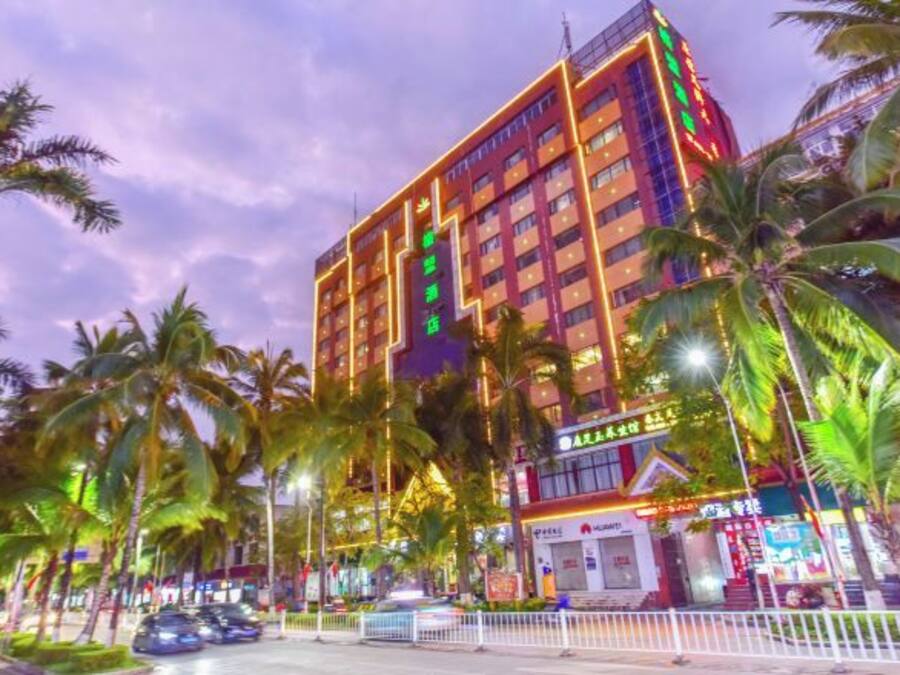 A multi-story hotel with a prominent sign, surrounded by palm trees and street lights.