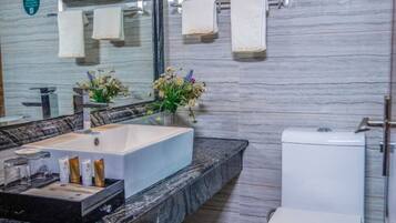 Ein Badezimmer mit Marmorplatte, Waschbecken, Toilette und Handtüchern an einem Haken.