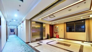 A hotel corridor with a patterned carpet, a marble floor, and a modern ceiling design. - Gemeng Hotel (Xishuangbanna Xuanwei Avenue) (Jinghong)