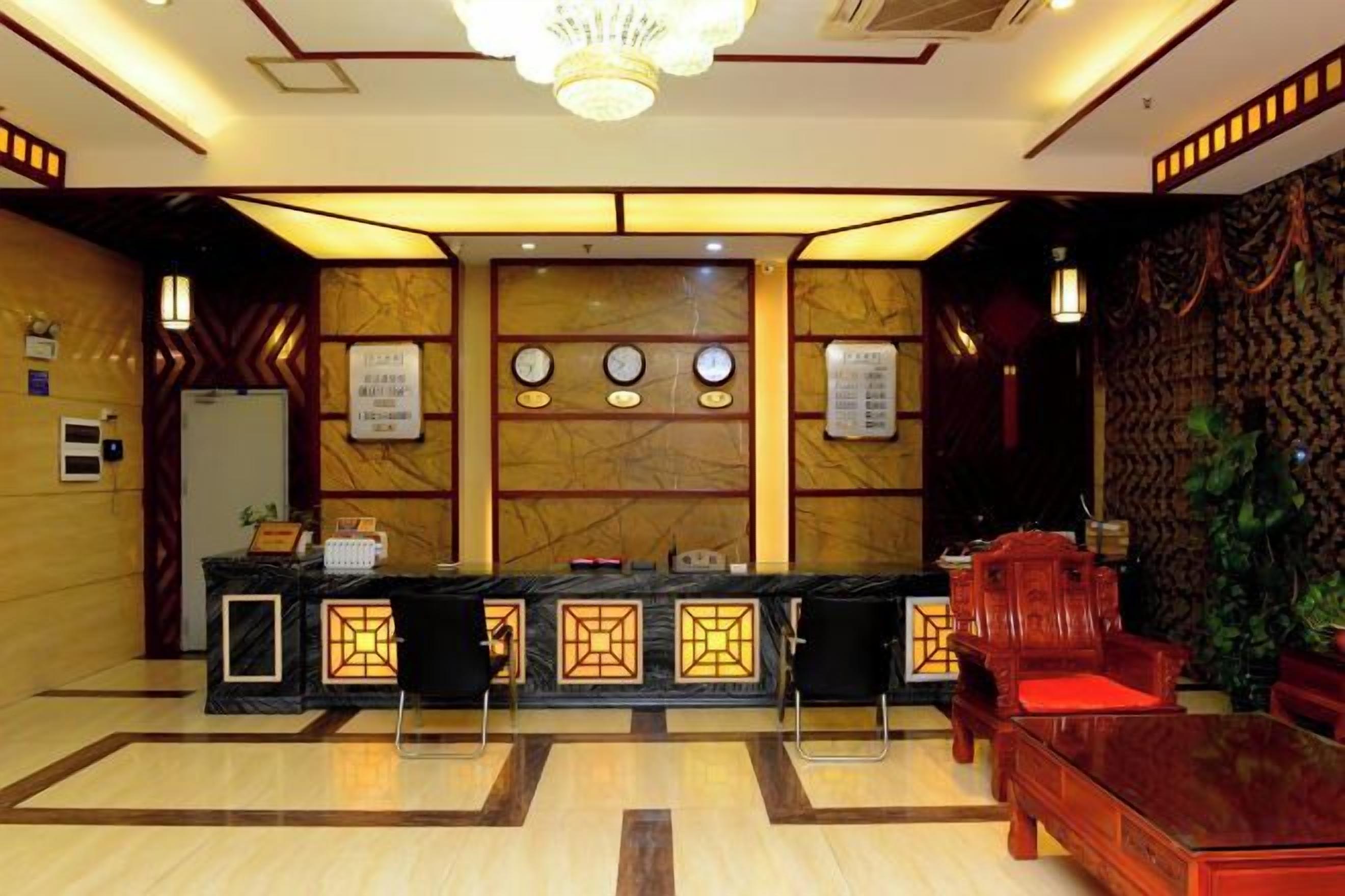 A reception area with a marble wall, a reception desk, and a seating area with a red sofa.