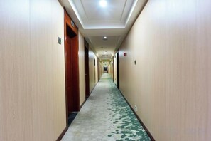 A hotel hallway with carpeted floors, doors on both sides, and a ceiling light. - Gemeng Hotel (Xishuangbanna Xuanwei Avenue) (Jinghong)