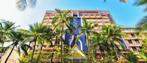 A multi-story hotel with a prominent entrance, surrounded by palm trees.