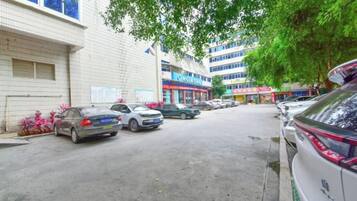Un parking avec des voitures, un bâtiment avec une enseigne et un arbre.