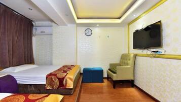 A hotel room with a bed, a TV, a chair, and a desk.