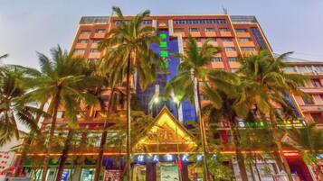 A multi-story hotel with a central atrium, palm trees, and a prominent entrance with a decorative arch.