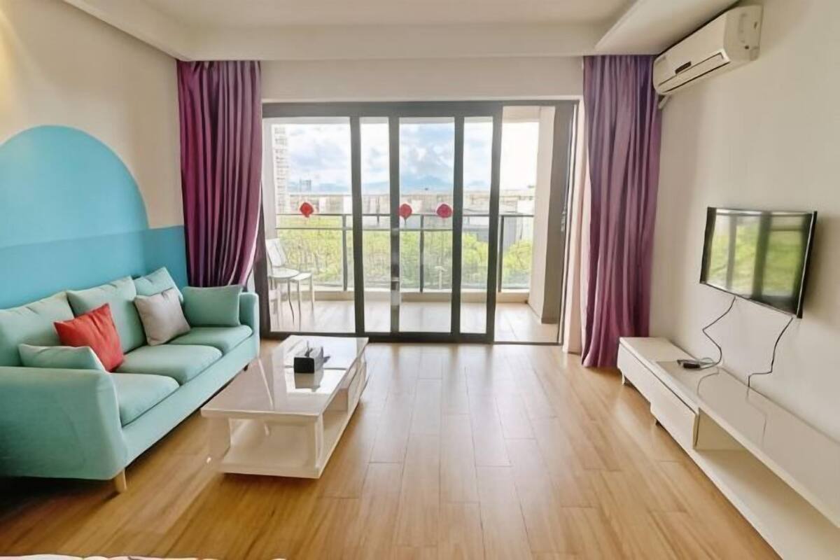 Een moderne woonkamer met een bank, salontafel, televisie en een balkon met uitzicht.