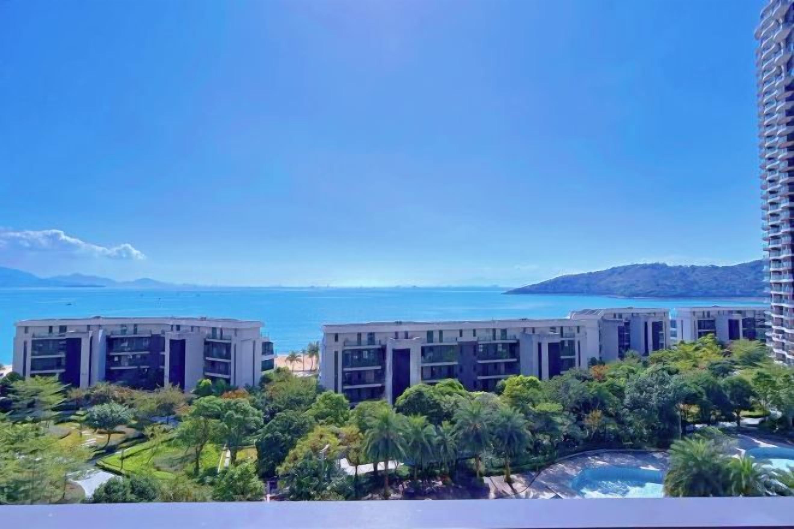 Une vue d’un hôtel composé de plusieurs bâtiments, avec une piscine et un ciel bleu dégagé.