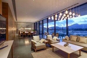 A modern hotel room with a large window, a dining area, and a seating area with sofas and a coffee table. - Relais Boutique Apartment (Huizhou Huarun Xiaojingwan) (Huizhou)