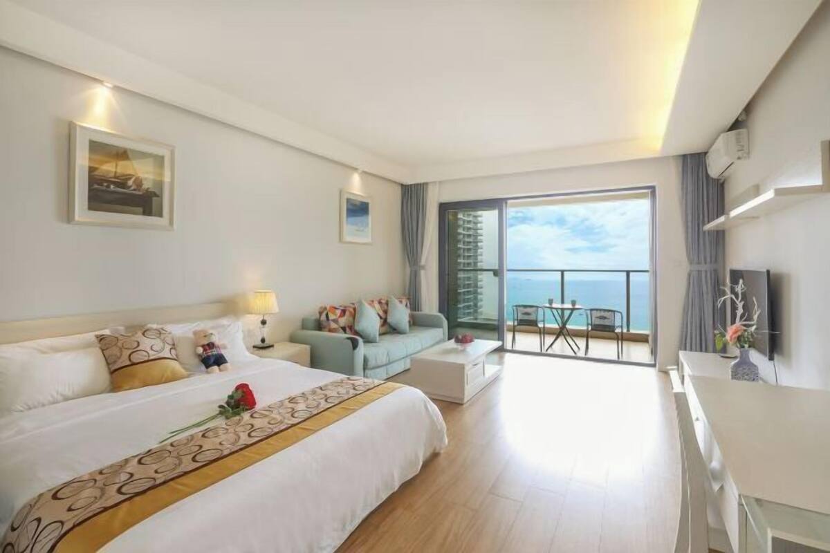 Een hotelkamer met een groot bed, een bank, een bureau en een balkon met uitzicht.