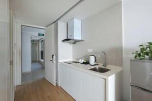 A modern kitchen with white cabinets, a stainless steel sink, a built-in range hood, and a refrigerator. - Relais Boutique Apartment (Huizhou Huarun Xiaojingwan) (Huizhou)