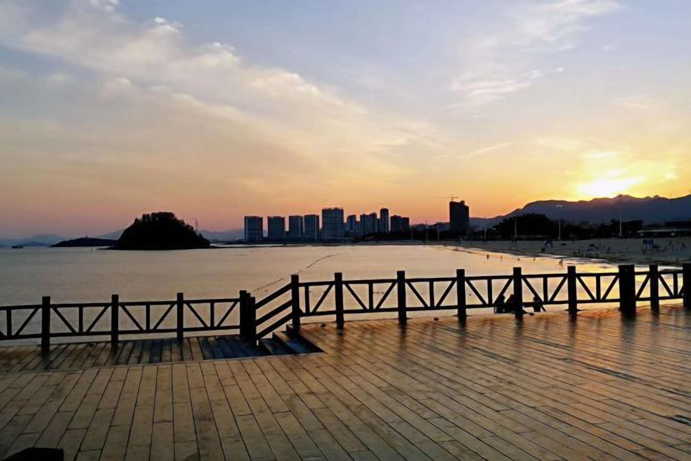 A waterfront promenade with a wooden deck and a metal railing.