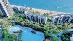 Un hôtel de grande hauteur doté d’une piscine entourée de verdure et offrant une vue sur la plage.
