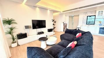 Ein modernes Wohnzimmer mit einem großen grauen Sofa, einem Flachbildfernseher und einem weißen Konsolentisch.