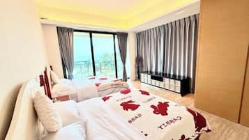 Ein Schlafzimmer mit Bett, Fernsehtisch und Blick ins Freie.