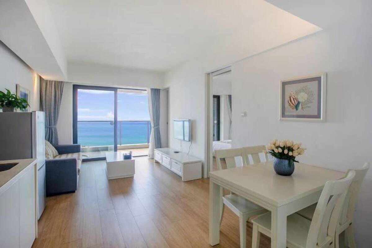 Een moderne woonkamer met een eetgedeelte, een televisie en uitzicht op zee.