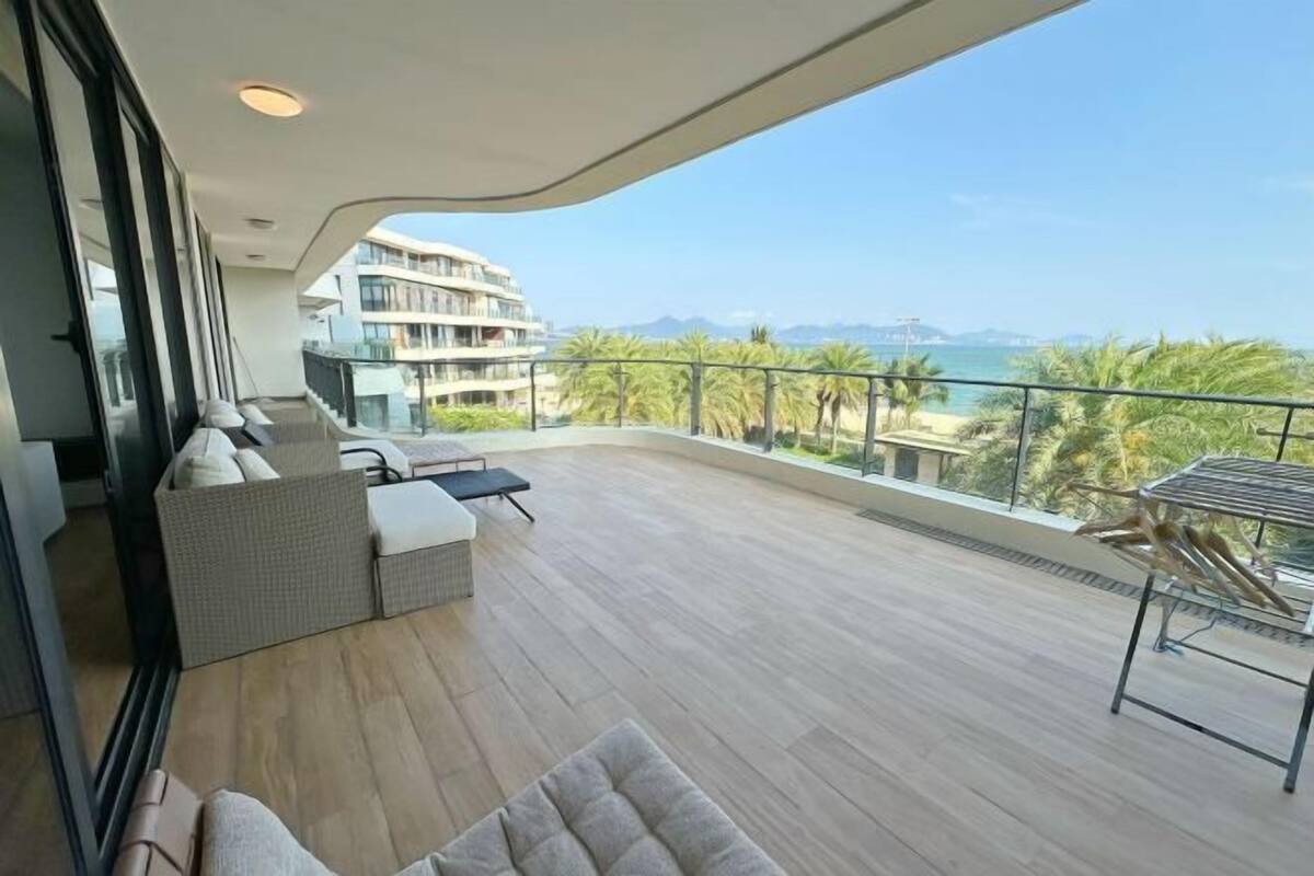 Een balkon met uitzicht op zee, een zithoek met kussens en een leuning.
