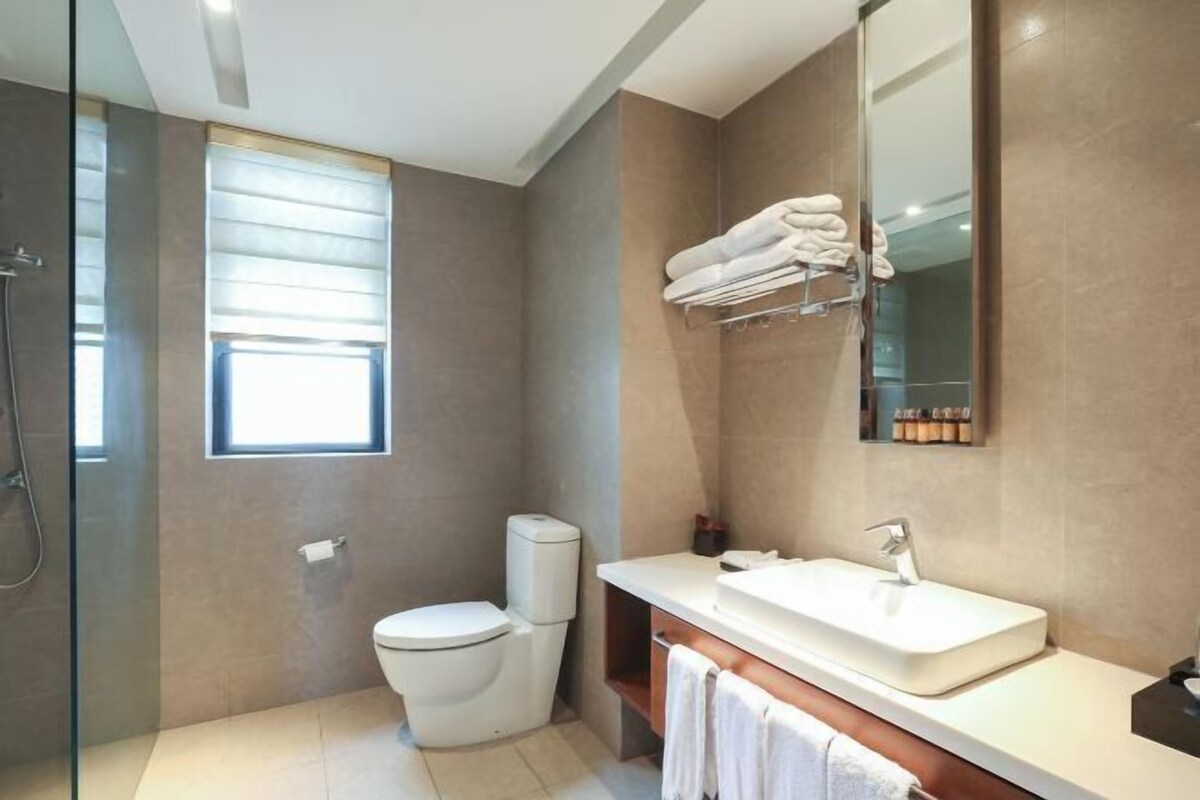 A modern bathroom with a toilet, shower, and sink.