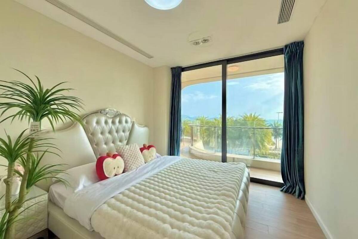 Een slaapkamer met een groot bed, een hoofdeinde, een raam met gordijnen en uitzicht op een balkon.