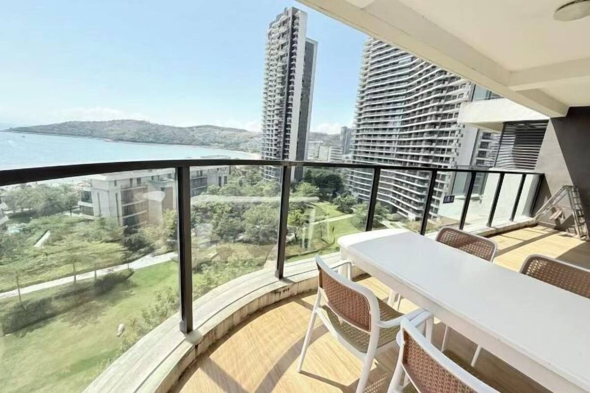 Een balkon met een tafel en stoelen, met uitzicht op een stadsbeeld en een wateroppervlak.