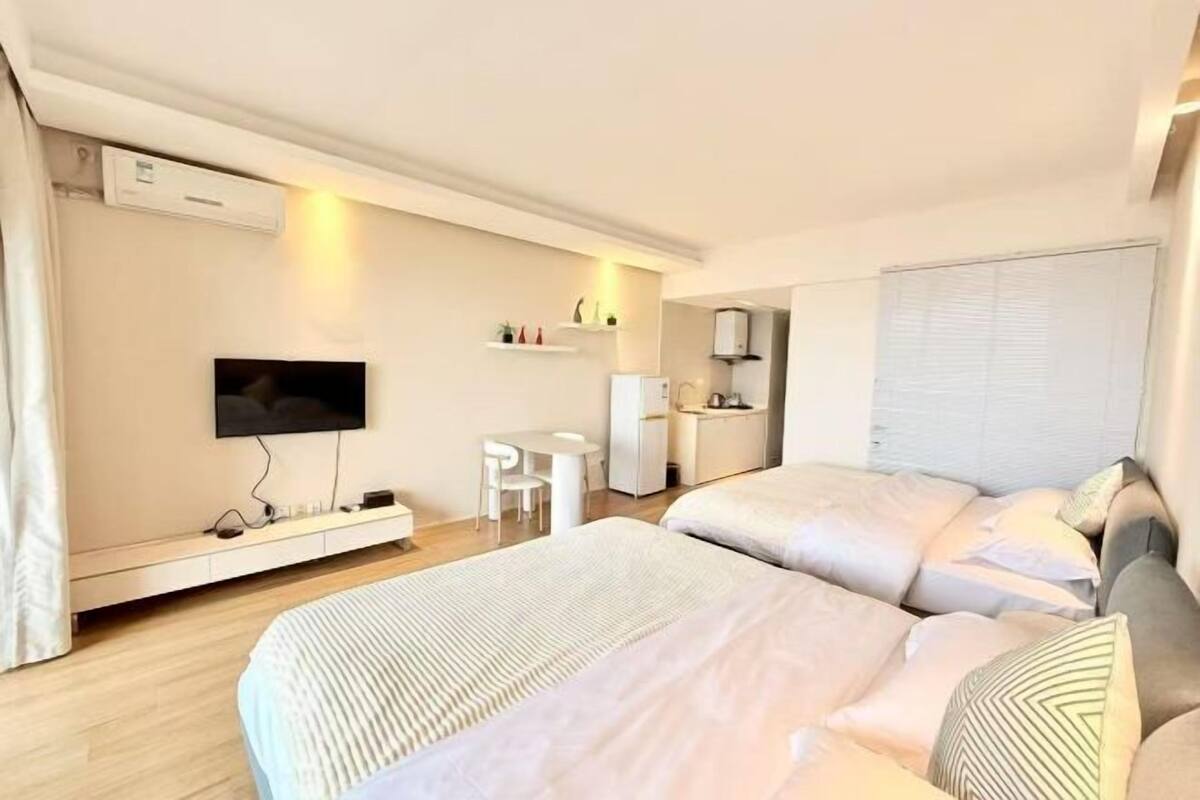 Een hotelkamer met twee bedden, een televisie, een klein tafeltje en een kitchenette.