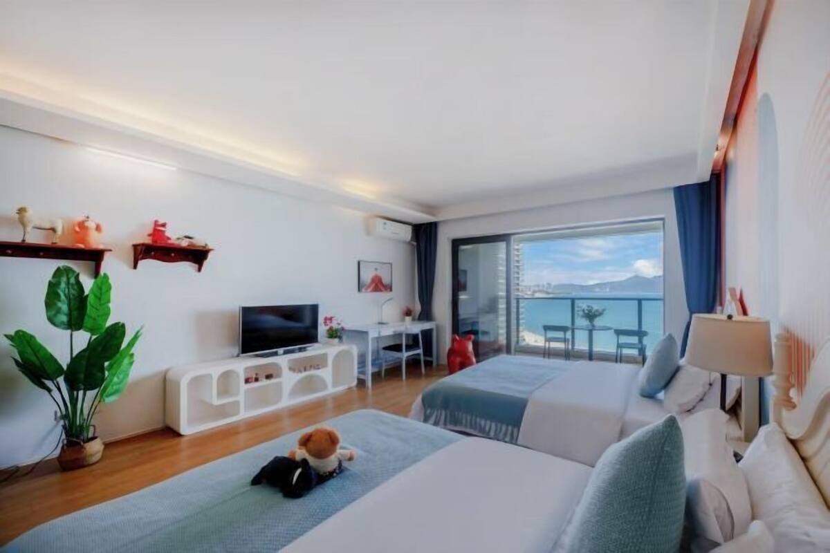 Een moderne hotelkamer met een groot raam, een flatscreen televisie, een bureau en twee bedden.