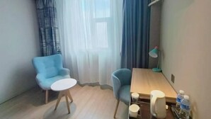 A small, modern room with a wooden floor, two blue armchairs, a white table, a lamp, and a water bottle. - HomeInn·neo（Linyi Hedong District government store） (Linyi)
